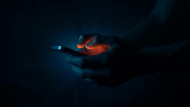 Man Holding a Mobile Phone in the Dark