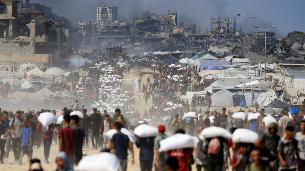 Palestinians gather as they carry aid supplies that entered Gaza through Israel, amid a hunger crisis, in Beit Lahia in the northern Gaza Strip July 20, 2025.