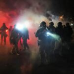 Law enforcement officers stand amid tear gas at the scene of a reported shooting Wednesday.