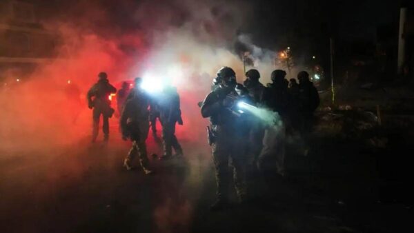 Law enforcement officers stand amid tear gas at the scene of a reported shooting Wednesday.