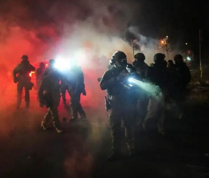 Law enforcement officers stand amid tear gas at the scene of a reported shooting Wednesday.